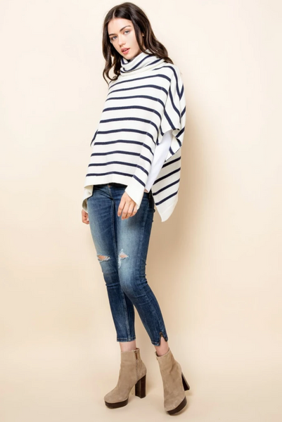 Turtleneck sweater poncho in ivory with navy stripes paired with jeans and booties.