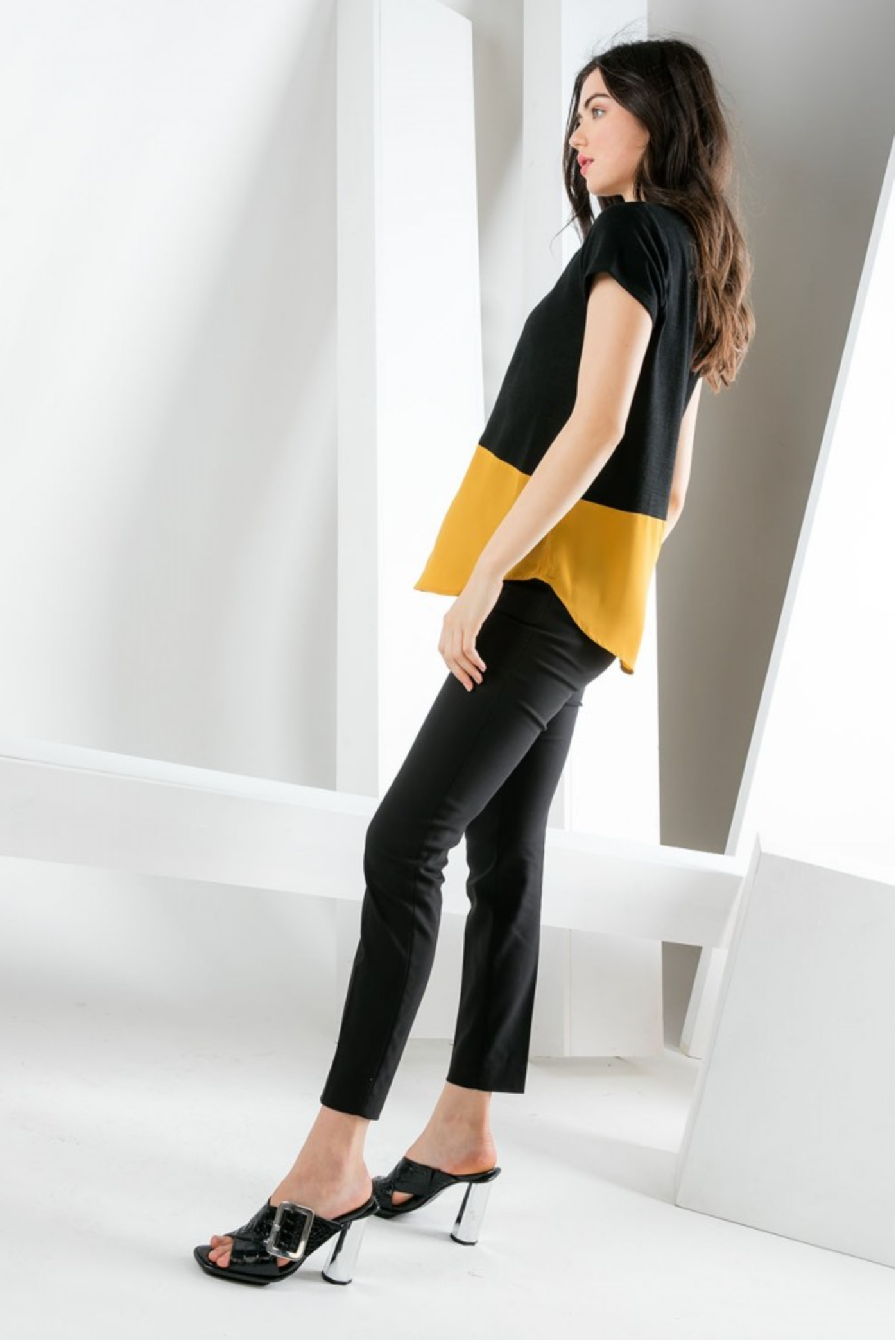 Side view of women&#39;s short sleeve black and gold contrast hem top with rounded hemline.