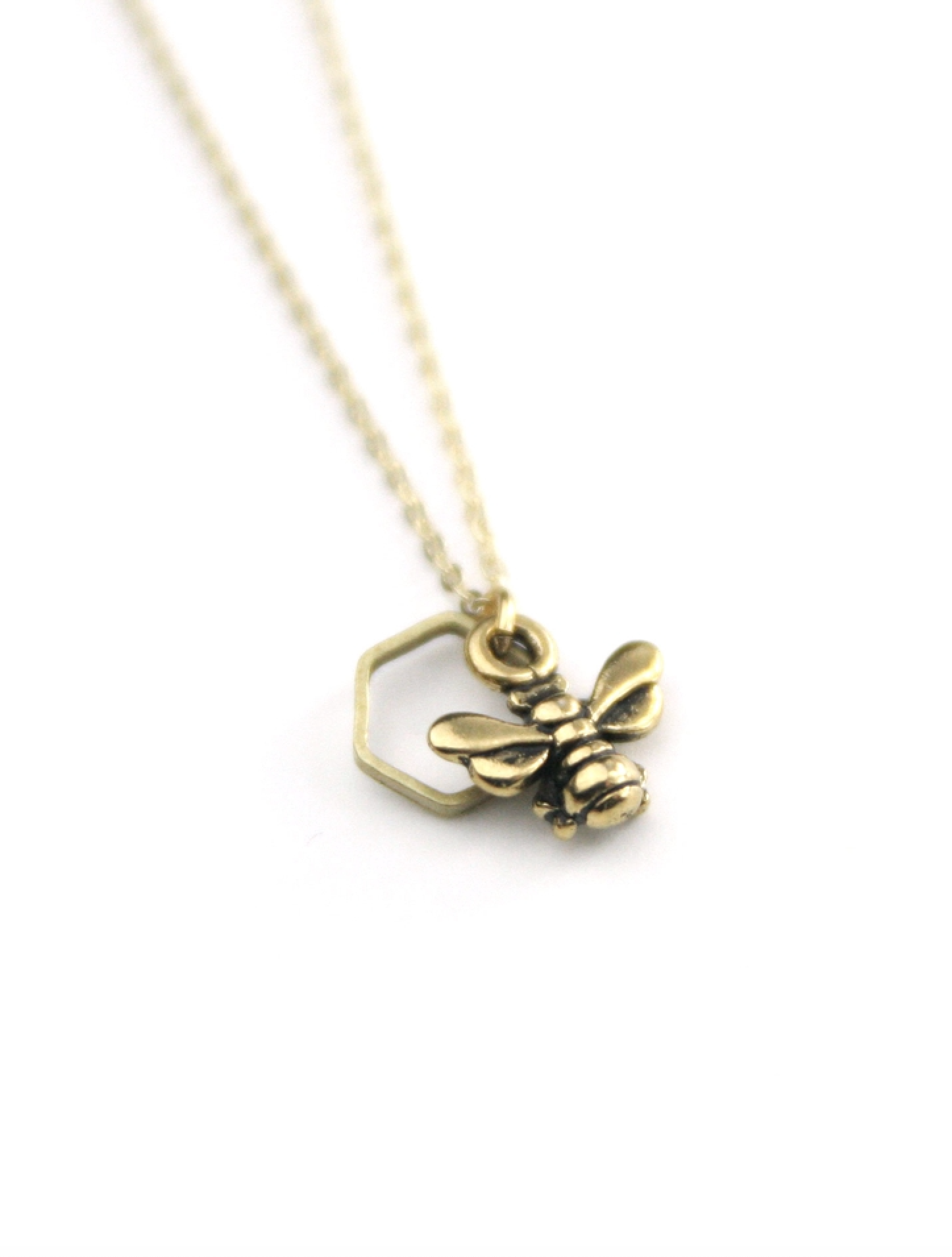 Gold honeybee and brass hexagon pendant necklace on gold chain.