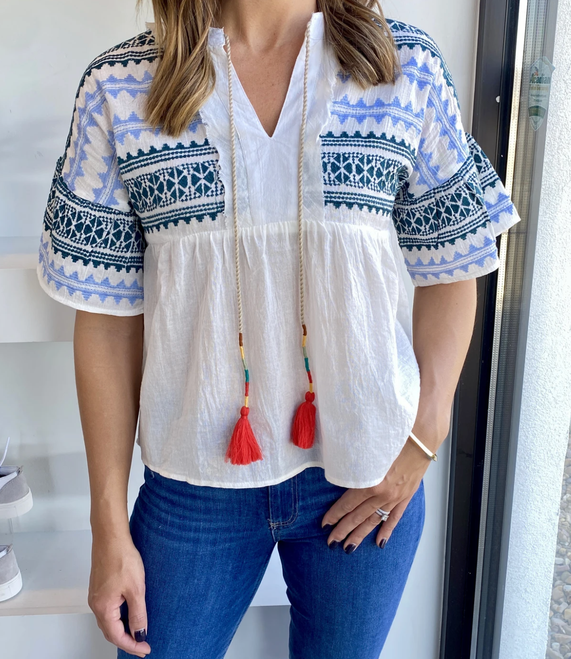 Blue and green embroidered shirt with colorful tassels and drop shoulder paired with jeans.