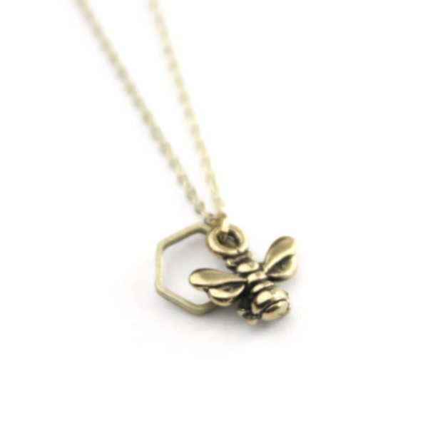 Gold honeybee and brass hexagon pendant necklace on gold chain.