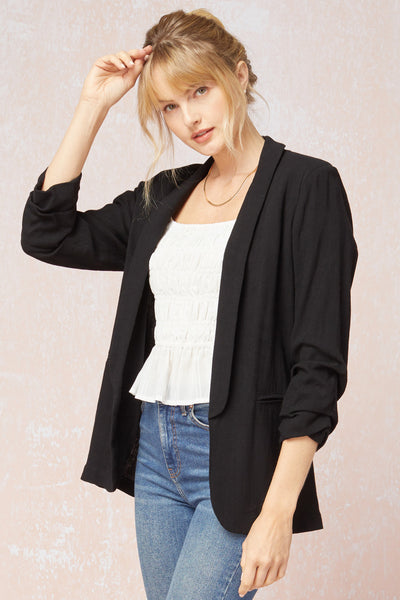 Women's black blazer with scrunched sleeves. Linen paired with white top and jeans.