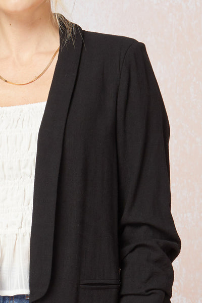 Front view of lapel on Women's black blazer with scrunched sleeves. Linen.