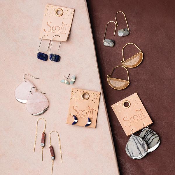 Stone earrings on display board.