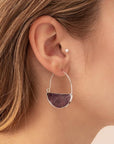 Stone hoop earrings in amethyst and silver on model.