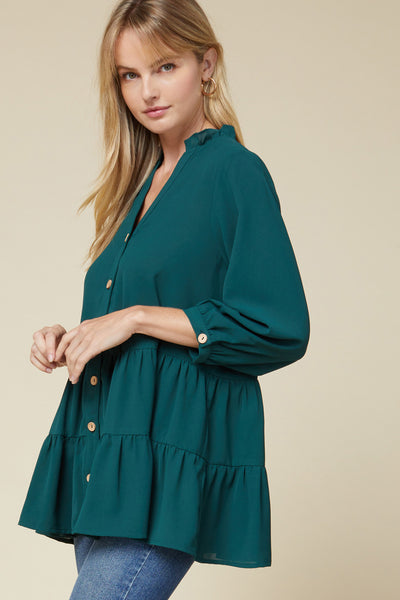 Side view of loose fit teal v-neck button up 3/4 sleeve tunic paired with jeans.