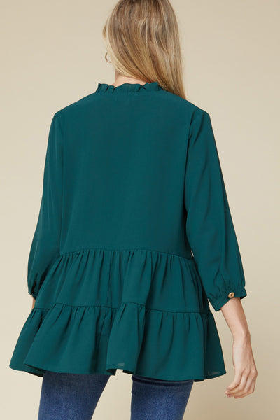 Rear view of teal 3/4 sleeve tiered tunic with ruffle detail at collar.