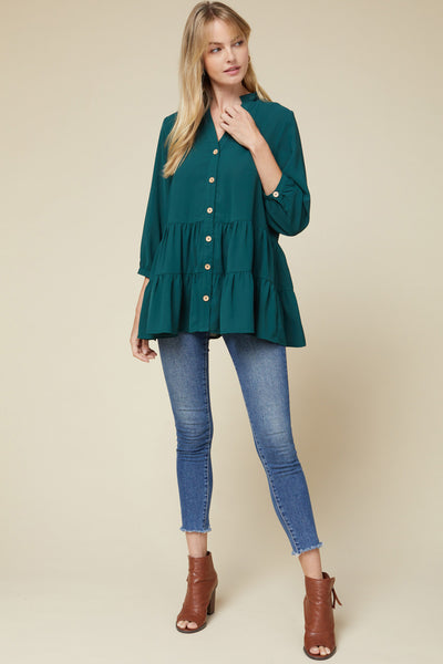 Full view of teal v-neck button up 3/4 sleeve tiered tunic paired with jeans and brown booties.