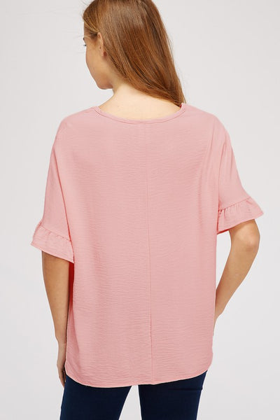 Back view of dolman sleeve top with ruffle with vertical seem at center of back. Length covers rear.