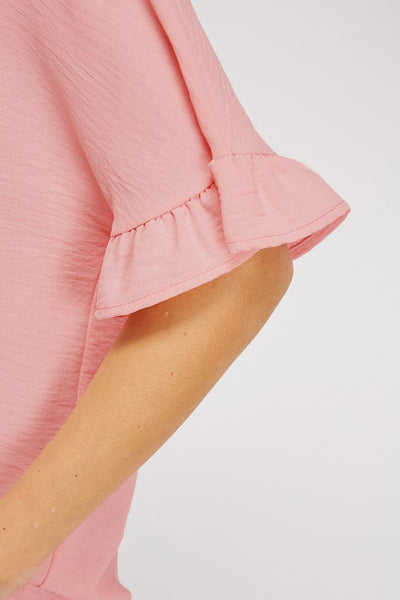 Close up view of textured mauve material on dolman sleeve and ruffle.
