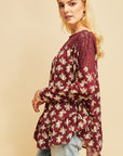 Side view of burgundy floral boho top with rounded hi-lo ruffle hem and crochet detail at neck and shoulder.