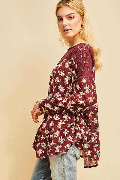 Side view of burgundy floral boho top with rounded hi-lo ruffle hem and crochet detail at neck and shoulder.