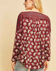 Back view of burgundy floral top with ruffle hem with full coverage length. Crochet across neck and shoulders is semi-sheer.