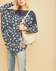 Long sleeve boho top in pretty blue color with white floral print with blue crochet detail along neck and shoulders.