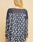 Back view of blue top with white flowers with crochet along neck and shoulders. Boho style with ruffle along hemline.