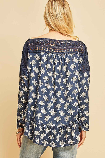 Back view of blue top with white flowers with crochet along neck and shoulders. Boho style with ruffle along hemline.