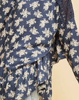 Close up view of ruffle detail along hemline and side seem in blue with white flowers.