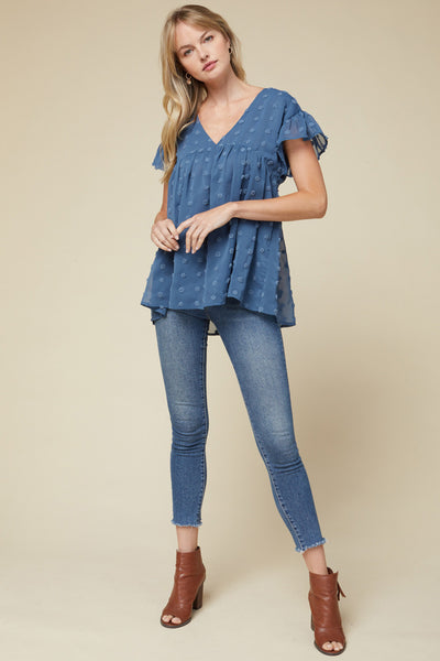 women's lightweight top - blue v-neck with ruffle sleeve hanging past hips paired with blue jeans.