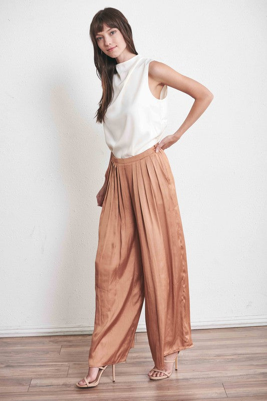 Satin feeling ivory sleeveless top with draped neck tucked into dressy pleated slacks and delicate heels.