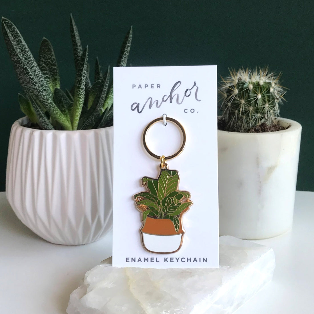 Gifts for plant lovers. Banana leaf keychain sitting in front of succulents.