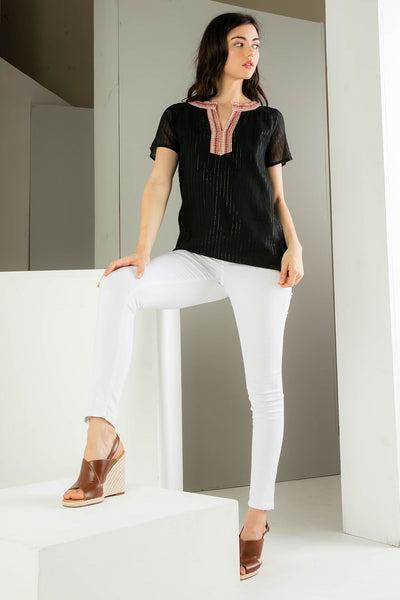 Embroidered black top. Paired with white denim and  and brown platforms.