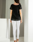 Back view of Embroidered black top. Paired with white denim. Embroidery around neck.