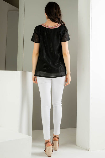 Back view of Embroidered black top. Paired with white denim. Embroidery around neck.