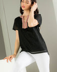 Embroidered black top. Paired with white denim with embroidery around neckline.