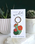 Gifts for a plant lover. Blooming cacti keychain on display card in front of other succulents.