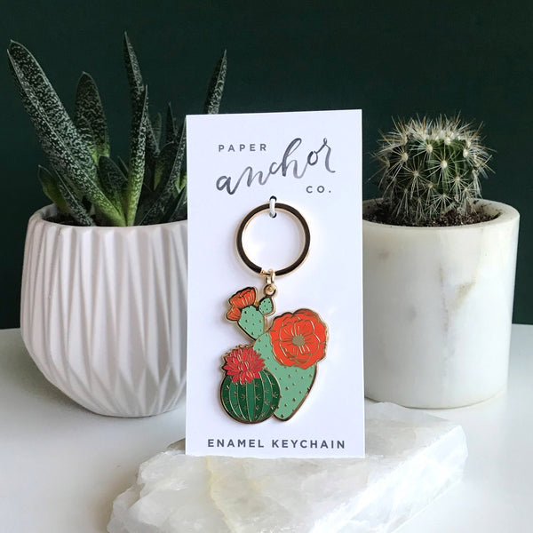 Gifts for a plant lover. Blooming cacti keychain on display card in front of other succulents.
