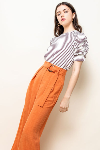 Short sleeved ruched white top with maroon stripes paired with colorful slacks.