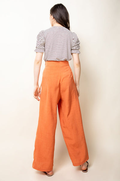 Back view of ruched short sleeve shirt paired with orange slacks.