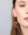 Lightweight hoop earrings worn by model in gold.