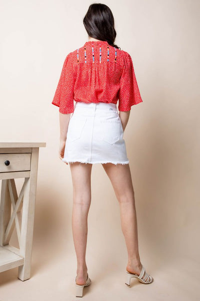 Back view of embroidered bell sleeve blouse on model.