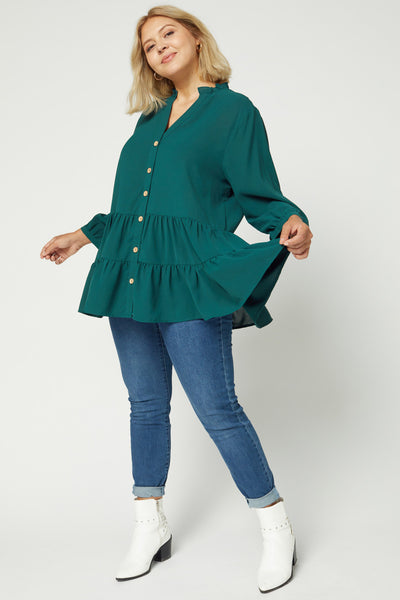 Full view of plus size teal tiered tunic paired with jeans and booties.