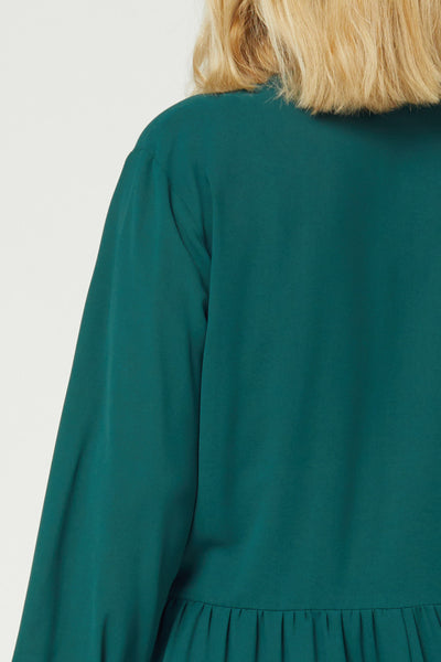 Close up view of back of loose fitting tiered tunic in plus size in teal.