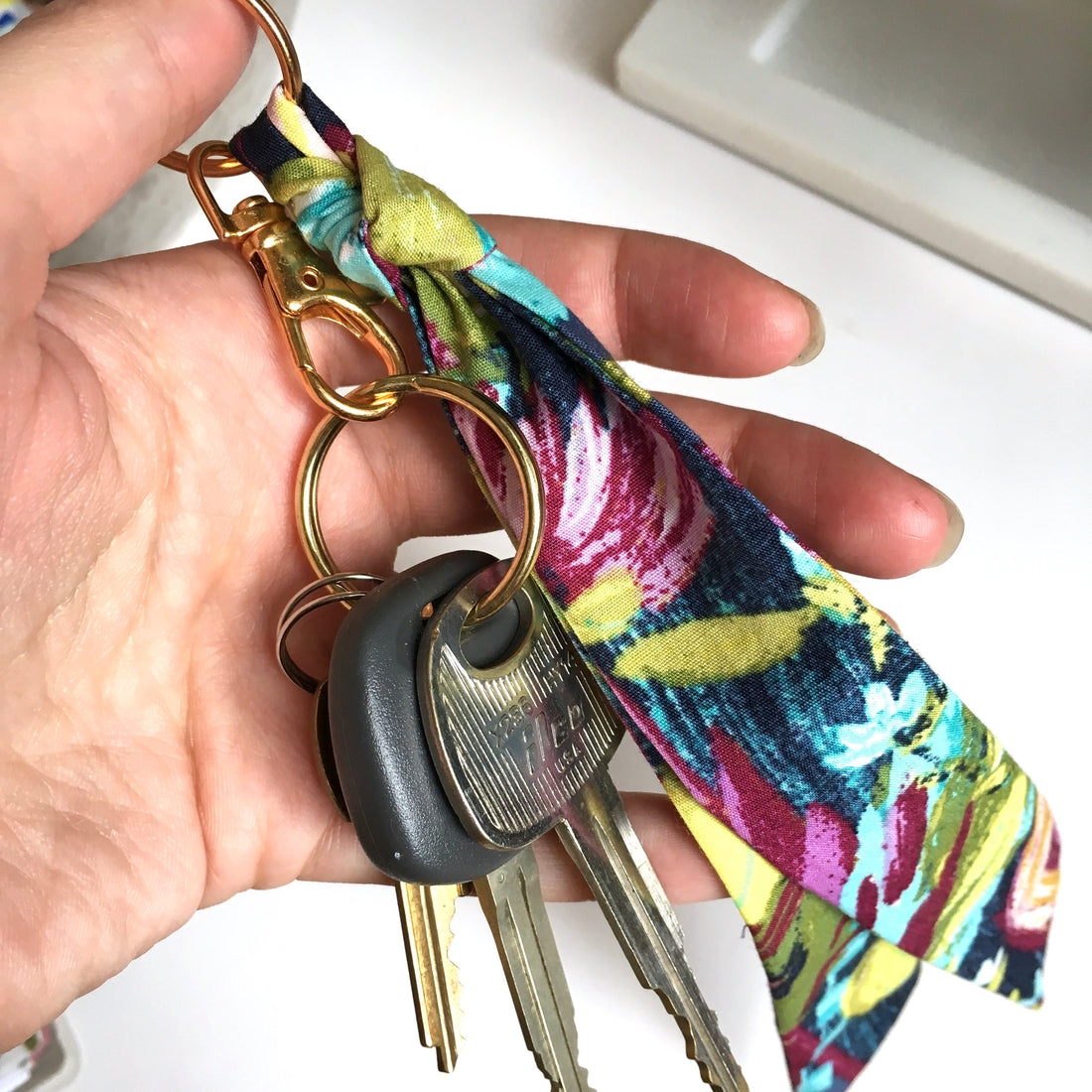 Scarf key chain in lilac floral print hooked to keys.