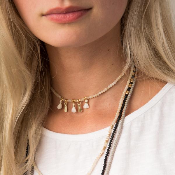 Close up of Delicate boho jewelry as metallic tassel wrap worn by model with short and long layered look.