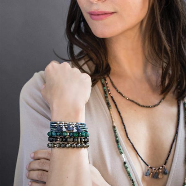 Delicate boho jewelry paired metallic tassel wrap with other beaded pieces as worn by model.