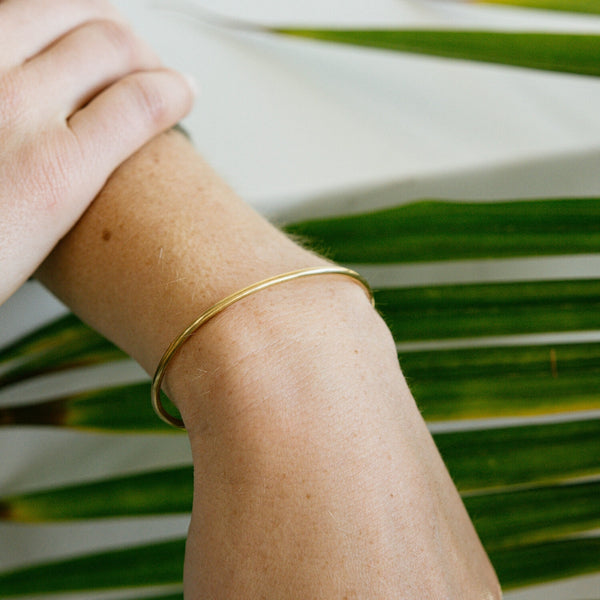 Minimalist gold bracelet shown on wrist. Brass cuff.