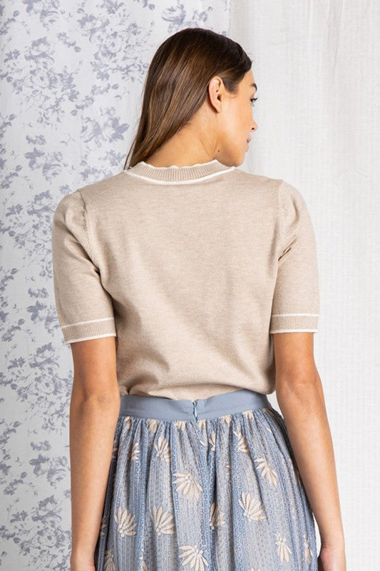 Back view of Short sleeve sweater women&#39;s top in oatmeal color tucked into blue skirt.