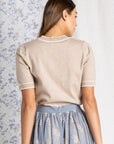 Back view of Short sleeve sweater women's top in oatmeal color tucked into blue skirt.