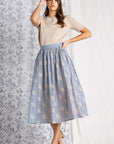 Short sleeve sweater women's top in oatmeal color paired with blue and tan skirt.