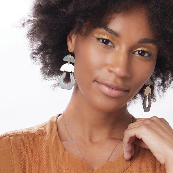 Model wearing gold stone chandelier earrings in aqua terra and gold.