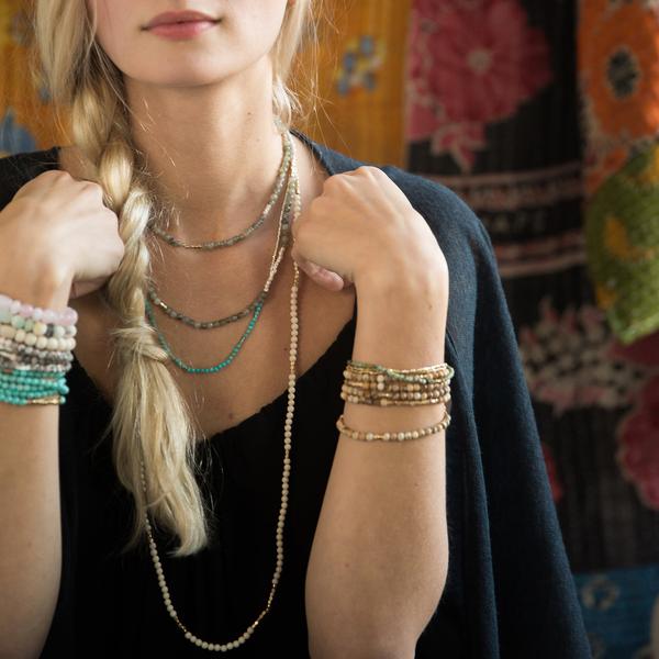 Women's turquoise bohemian jewelry. Model wearing several different stone wraps including this turquoise and gold wrap.