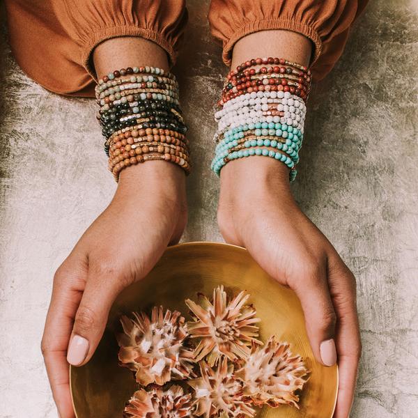 Women&#39;s turquoise bohemian jewelry. Model wearing several stone wraps stacked as bracelets on both wrists.