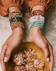 Women's turquoise bohemian jewelry. Model wearing several stone wraps stacked as bracelets on both wrists.