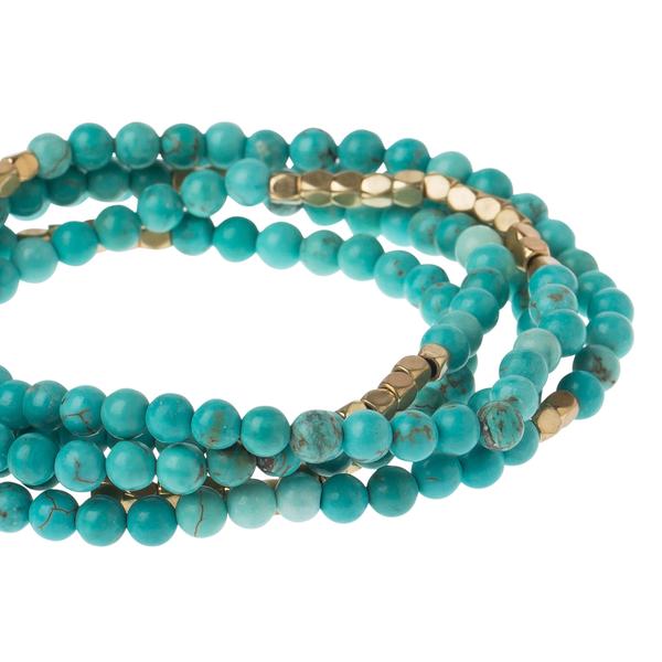 Women's turquoise bohemian jewelry. Close up view of turquoise and gold stone wrap.