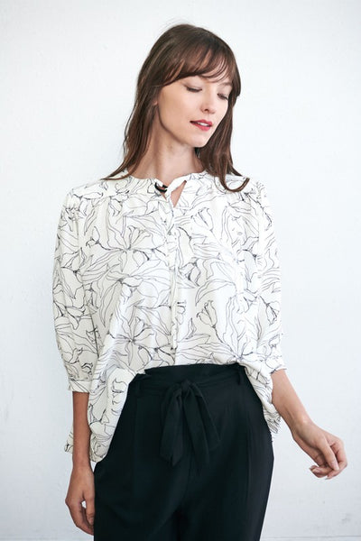 Womens black and white blouse paired with black pants.